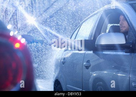 Kaufmann im Auto erreichen für Paket im Regen Stockfoto