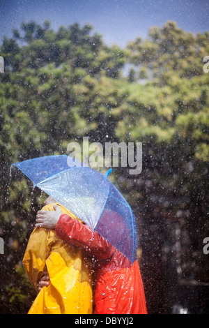 Paar umarmt unter Dach im Regen Stockfoto
