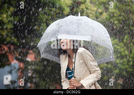 Glückliche Frau unter Dach im Regen Stockfoto