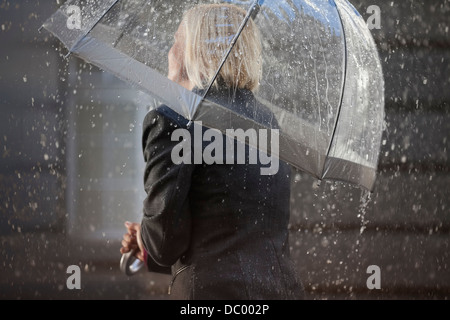 Geschäftsfrau unter Dach im Regen Stockfoto
