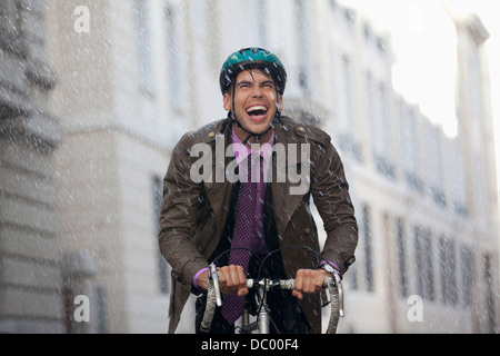 Begeisterte Unternehmer Reiten Fahrrad im Regen Stockfoto