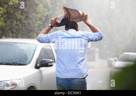 Manndeckung Kopf mit Zeitung im verregneten Straße Stockfoto