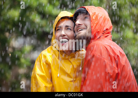 Glückliches Paar in Regenmäntel blickte zu Regen Stockfoto