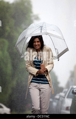 Glückliche Frau unter Dach im Regen Stockfoto