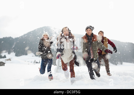 Glückliche Freunde spielen in schneebedecktes Feld Stockfoto