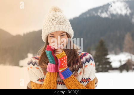 Porträt von lächelnden Frau mit Stricken Hut in schneebedecktes Feld Stockfoto