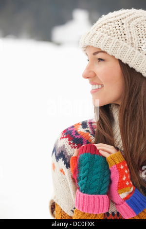 Nahaufnahme der lächelnde Frau mit Stricken Hut und fingerlose Handschuhe in schneebedecktes Feld Stockfoto