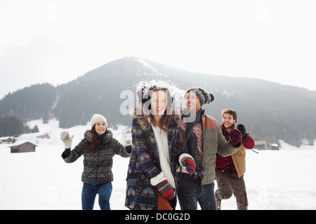 Verspielte Freunde genießen Schneeballschlacht im Feld Stockfoto