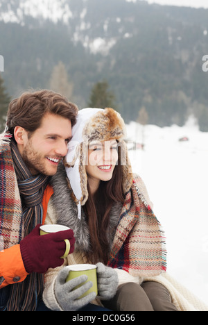 Glückliches Paar Kaffeetrinken in schneebedecktes Feld Stockfoto