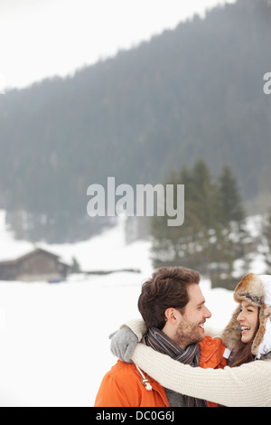 Glückliches Paar umarmt in schneebedecktes Feld Stockfoto