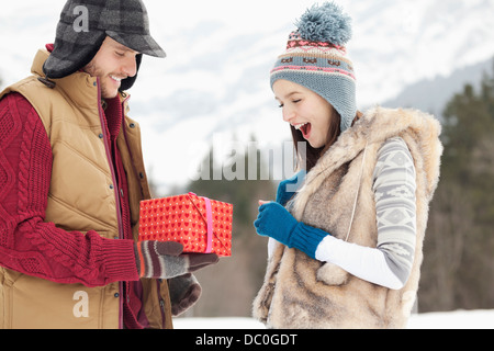 Mann Frau mit Geschenk in schneebedeckten Feld überraschend Stockfoto