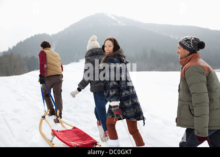 Glückliche Freunde ziehen Schlitten in schneebedecktes Feld Stockfoto