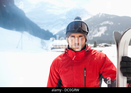 Portrait von zuversichtlich Mann mit Skiern in schneebedecktes Feld