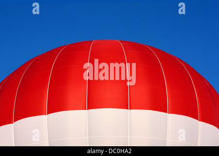 Nahaufnahme des oberen Teil des roten und weißen Heißluftballon fliegen vor einem brillanten blauen Sommerhimmel. Stockfoto