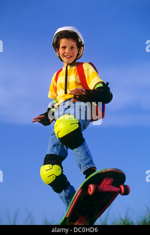 1990ER JAHRE JUNGE SKATEBOARD TRAGEN SAFETY GEAR PADS UND HELM BLICK IN DIE KAMERA Stockfoto