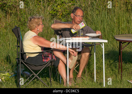 Ein paar draußen sitzen in einer Mahlzeit in der warmen Sonne an der Küste von Le Crotoy in der Somme, Picardie, Frankreich. Stockfoto