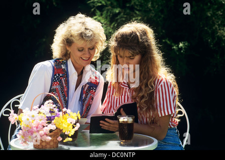 1990ER JAHREN MUTTER UND TEENAGER TOCHTER ZUSAMMEN LESEN BIBEL Stockfoto