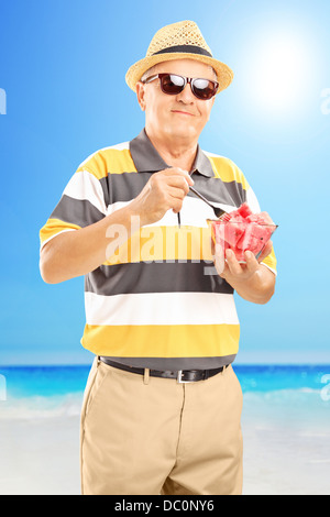 Ältere Gentleman hält eine Schale mit Wassermelone Scheiben und auf eine Sonne am Strand genießen Stockfoto