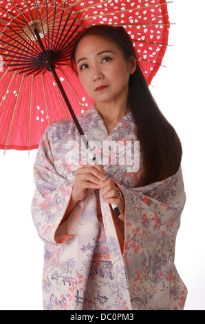 Japanische Dame trägt einen rosa und lila gemusterte Kimono und hält einen rote Sonne-Schatten. Stockfoto