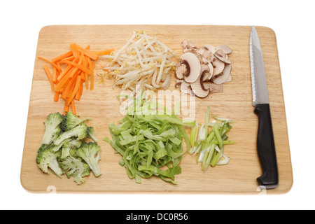 Gemüse unter Rühren braten Zutaten auf ein Schneidbrett aus Holz mit einem Messer isoliert gegen weiß Stockfoto