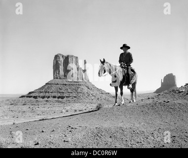 NAVAJO INDIAN COWBOY HUT AUF DEM PFERDERÜCKEN MIT FELSFORMATIONEN DES MONUMENT VALLEY IM HINTERGRUND Stockfoto