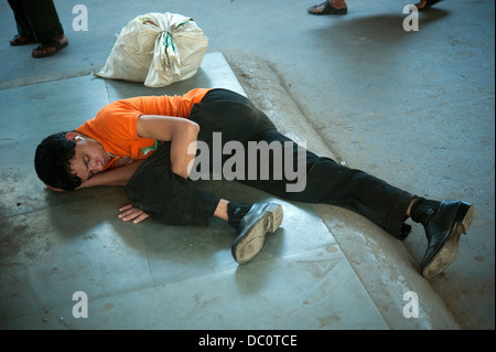 Junger Mann mit Ohrstöpsel schlafen auf dem Bahnsteig, Mumbai, Indien Stockfoto
