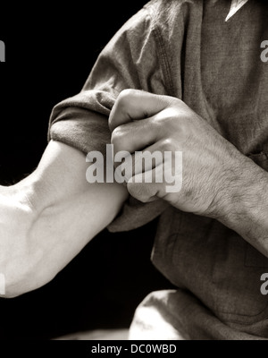 1920ER-1930ER JAHREN 1940ER JAHRE 1950ER JAHREN KOMMEN MANN SYMBOLISCHEN ÄRMEL AUFROLLEN, UM ZU ARBEITEN Stockfoto