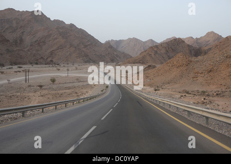 Eine Asphaltstraße fällt nach unten auf off Road Gelände des Wadi Khab al Shamis, Musandam, Oman Stockfoto