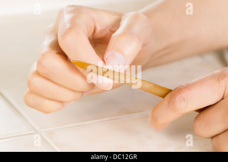 Horizontale Foto weibliche Hände mit goldenen Metall Nagelfeile Werkzeug vorne hautnah Stockfoto