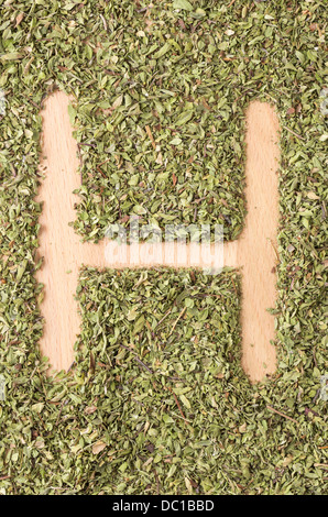 Buchstabe H geschrieben mit Oregano auf Holztisch Stockfoto