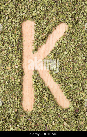 Buchstabe K geschrieben mit Oregano auf Holztisch Stockfoto