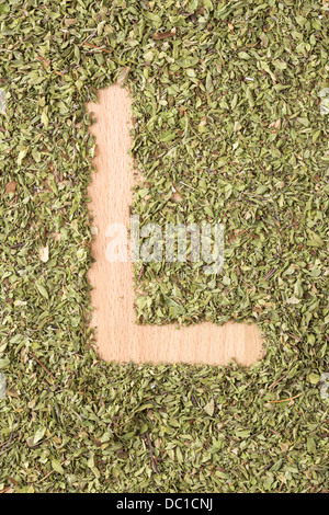 Buchstabe L geschrieben mit Oregano auf Holztisch Stockfoto