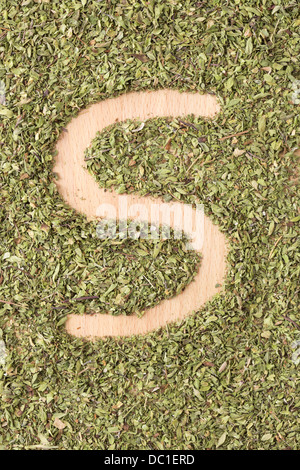 Buchstabe S geschrieben mit Oregano auf Holztisch Stockfoto