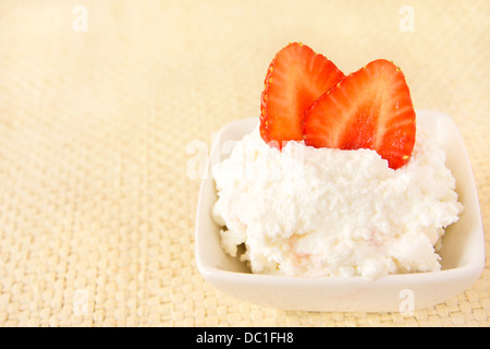 Frischer hausgemachter Hüttenkäse mit Erdbeere in weiße Schüssel auf Bambus Matte Textur, Nahaufnahme, Horizontal, Textfreiraum Stockfoto