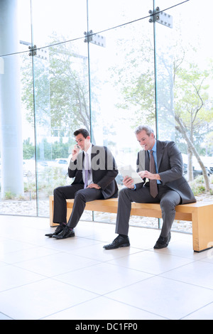 Geschäftsleute, die mit Handy und digital-Tablette in lobby Stockfoto