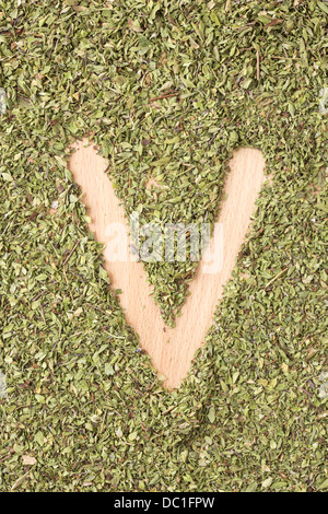 Buchstabe V geschrieben mit Oregano auf Holztisch Stockfoto