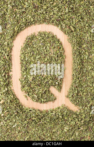 Buchstabe Q geschrieben mit Oregano auf Holztisch Stockfoto