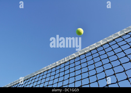 Tennisball über das Netz vor einem strahlend blauen Himmel fliegen Stockfoto
