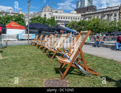 Zeile 8 hölzerne Liegestühle und Sonnenschirme auf dem Rasen in Piccadilly Gardens Greater Manchester Stockfoto