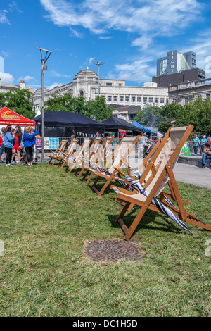 Reihe von hölzernen Liegestühle und Sonnenschirme auf dem Rasen in Piccadilly Gardens Greater Manchester Stockfoto