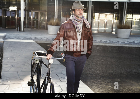 Mitte erwachsenen Mann zu Fuß mit dem Fahrrad in die Stadt Stockfoto