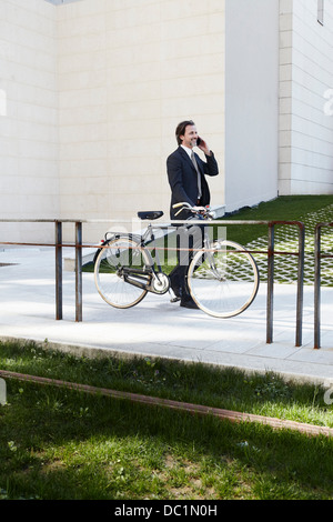 Mitte adult Geschäftsmann hält Fahrrad und Handy Stockfoto