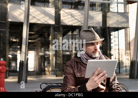 Mitte erwachsener Mann mit digital-Tablette und wegsehen Stockfoto