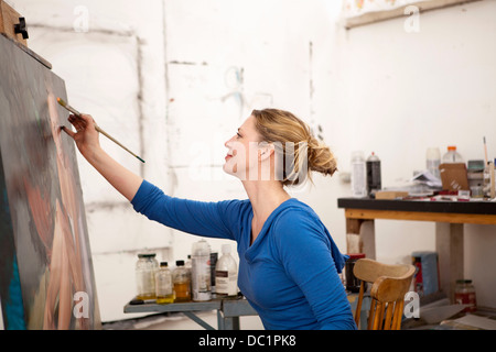 Mitte Erwachsene Frau malen auf Leinwand im Atelier des Künstlers Stockfoto