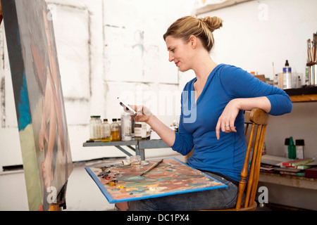 Mitte Erwachsene Frau mit Handy im Atelier des Künstlers Stockfoto