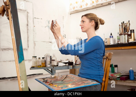 Mitte Erwachsene Frau fotografieren Ölgemälde im Atelier des Künstlers Stockfoto