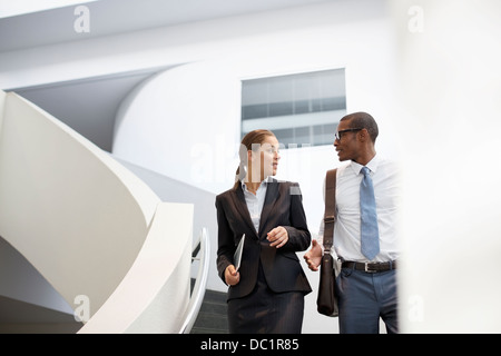 Geschäftsmann und Geschäftsfrau, die auf moderne Treppe im Gespräch Stockfoto