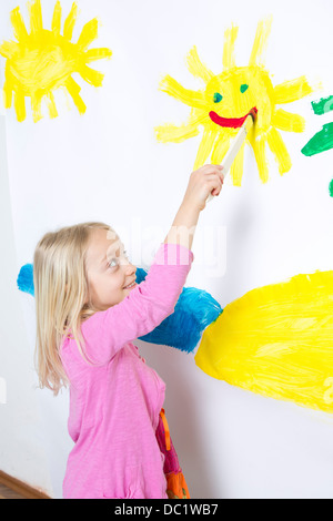 Junges Mädchen lächelnde Sonne auf Wand malen Stockfoto