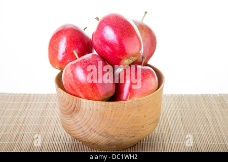 Rote Äpfel im Holz Schüssel und Bambus Tischset mit weißem Hintergrund Stockfoto