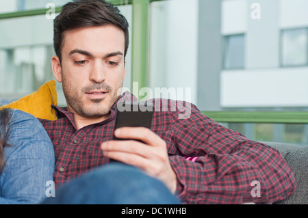 Junge Männchen zu Hause mittels Mobiltelefon Stockfoto